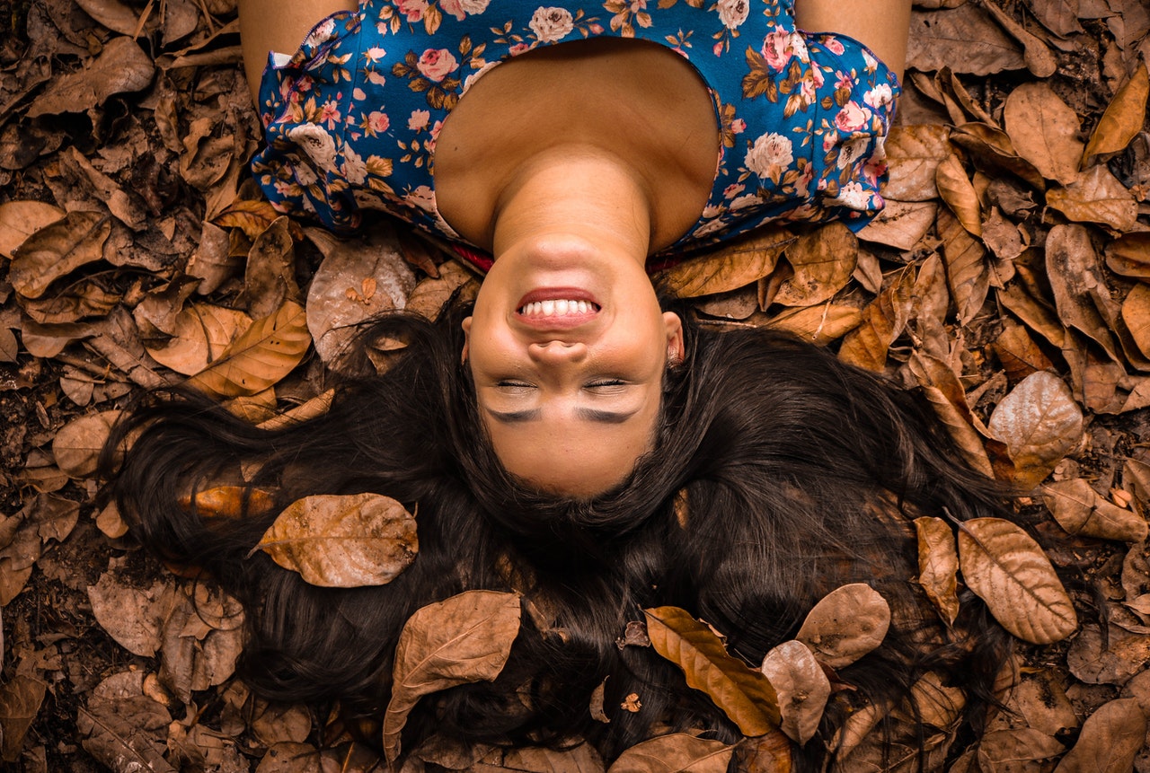 Woman laying happily in a pile of fall leaves