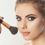 Beautiful young woman with powder brows holding a makeup brush