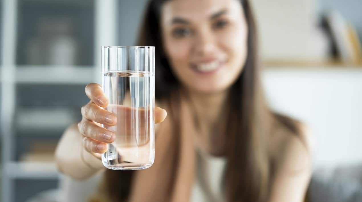 woman holding a tall glass of water - nutrition for skin health